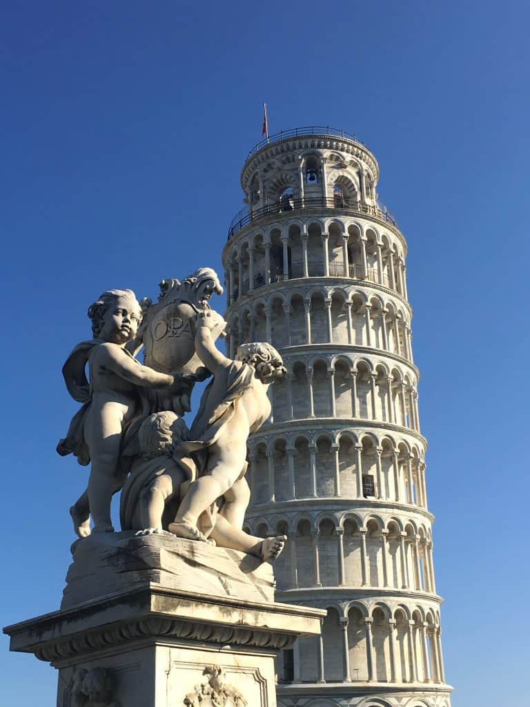 Statue of cherubs with Leaning Tower of Pisa in background