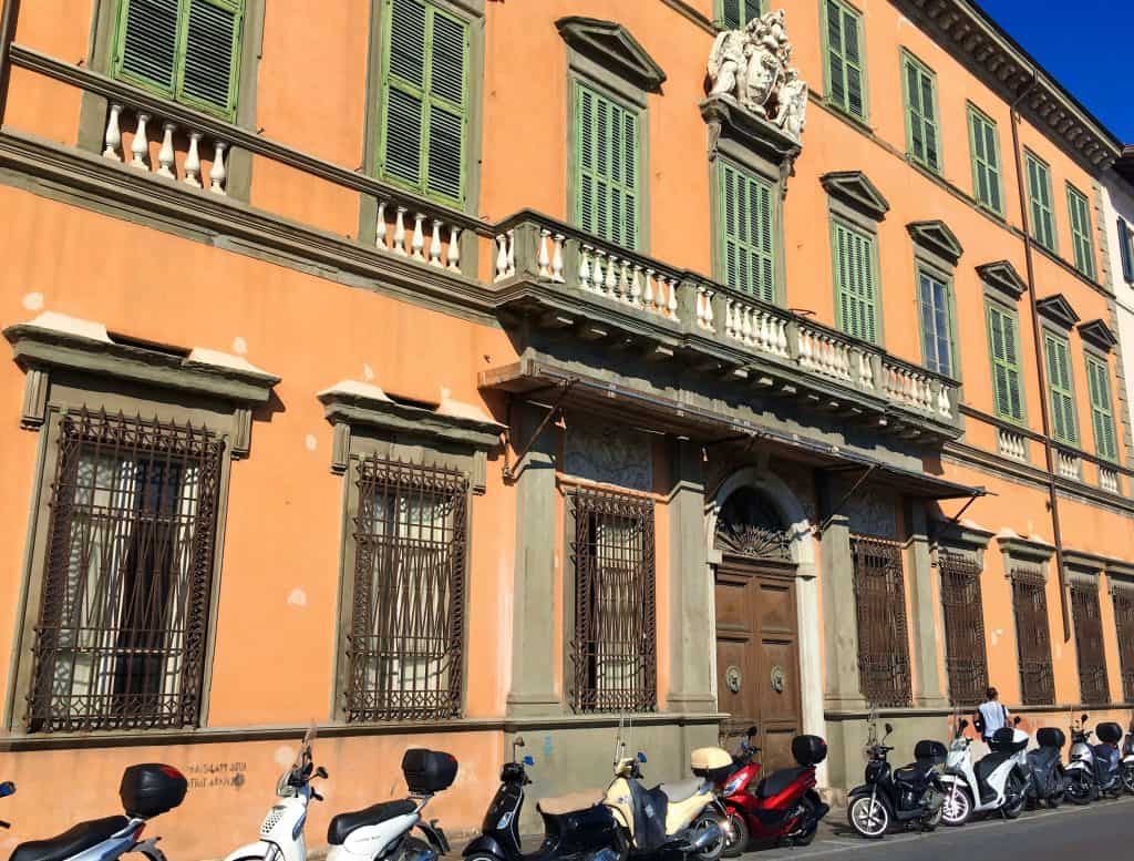 Terracotta building with motorcycles outside in Pisa
