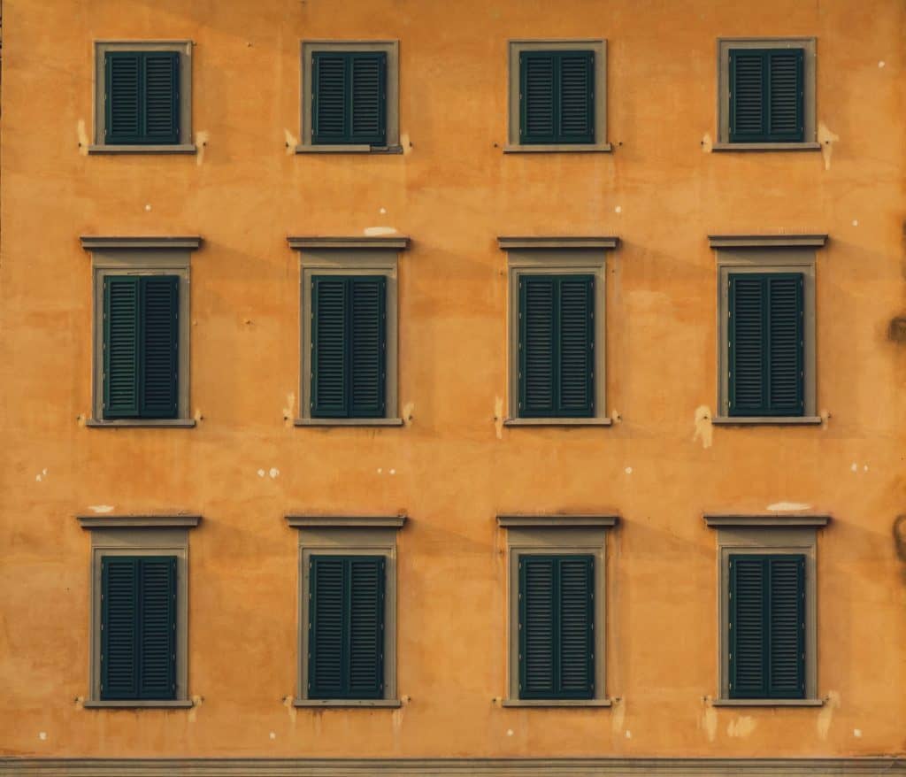 Terracotta Pisa building with green window shutters