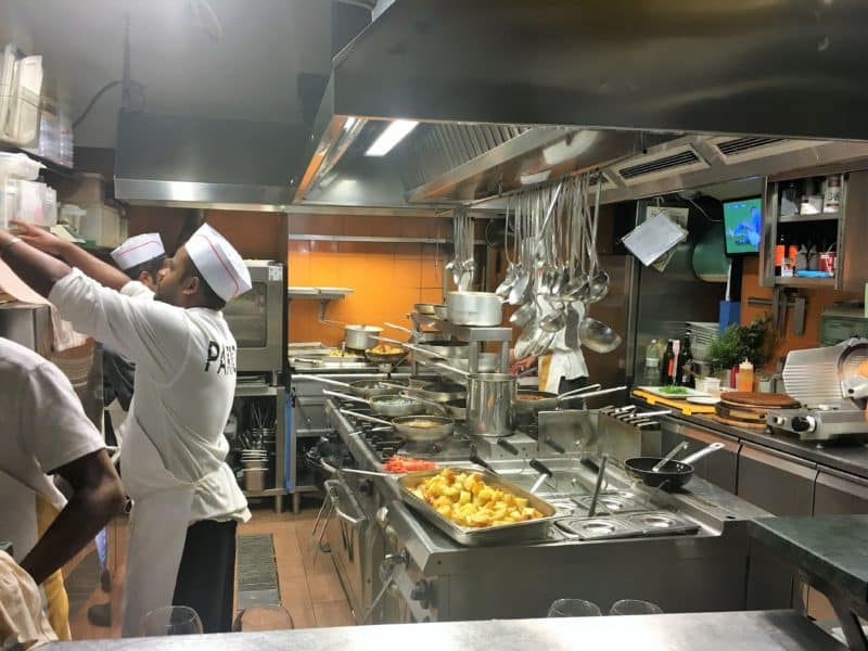 The kitchen space at Parione with chefs cooking to the left and ladles hanging in the central cooking station.