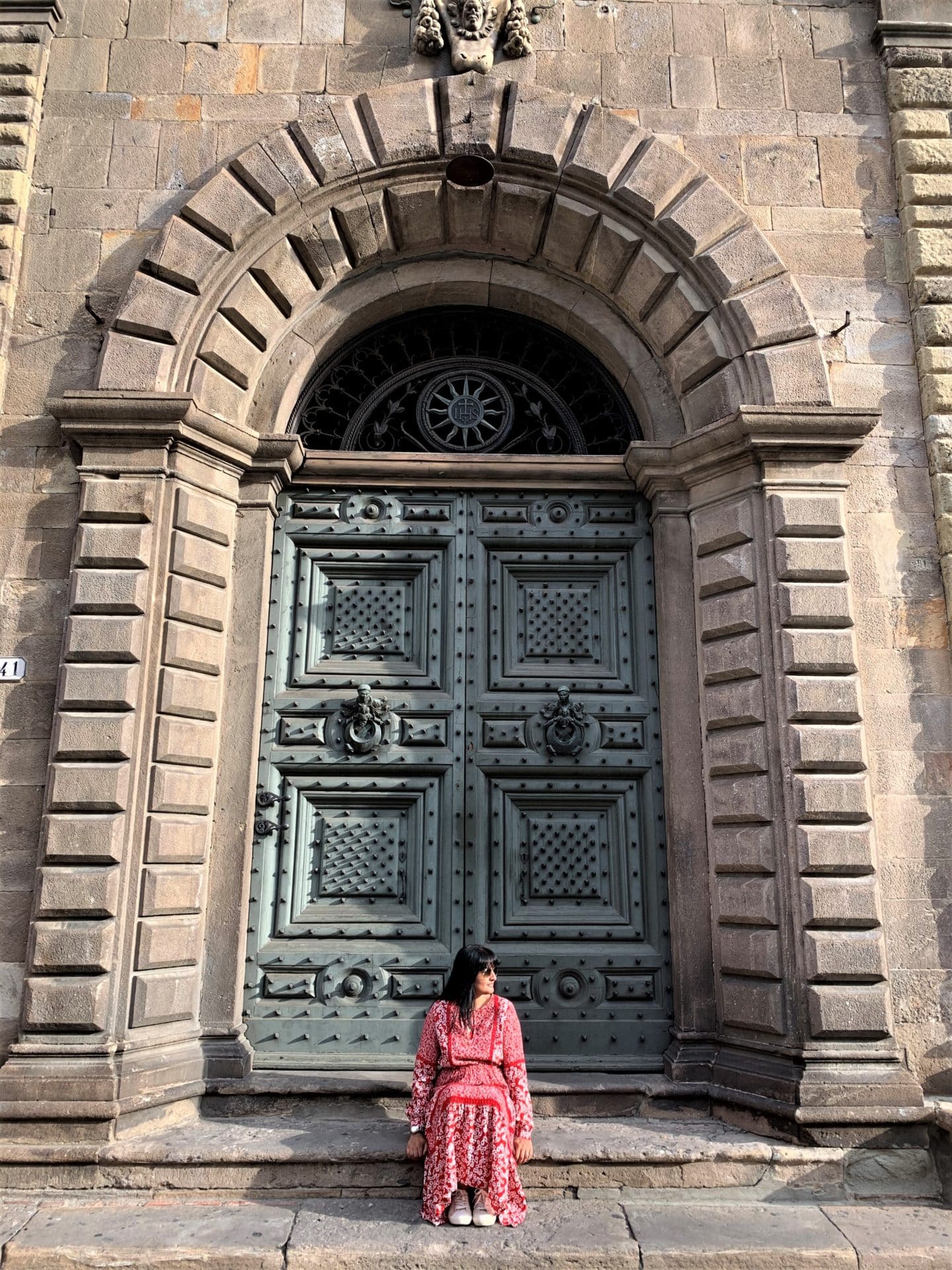 Bejal sitting in front of medieval green door in Lucca
