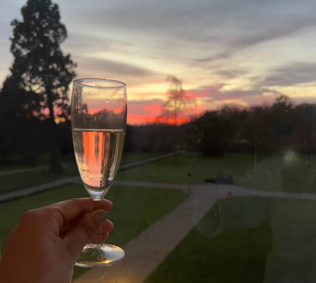 champagne glass with sunset behind from Baker Suite window