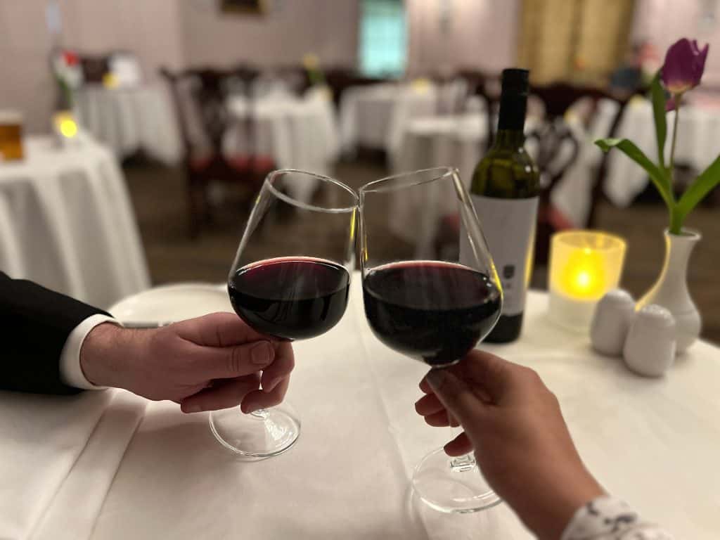 2 red wine glasses (Merlot, Malbec toasting at restaurant
