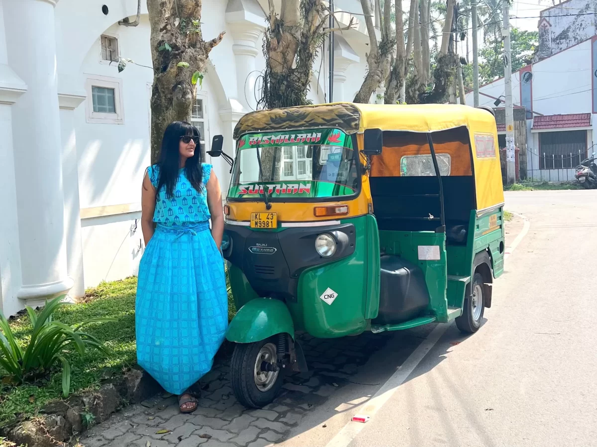 Bejal wearing a turquoise skirt and top standing in front of a automatic Rickshaw in Fort Kochi